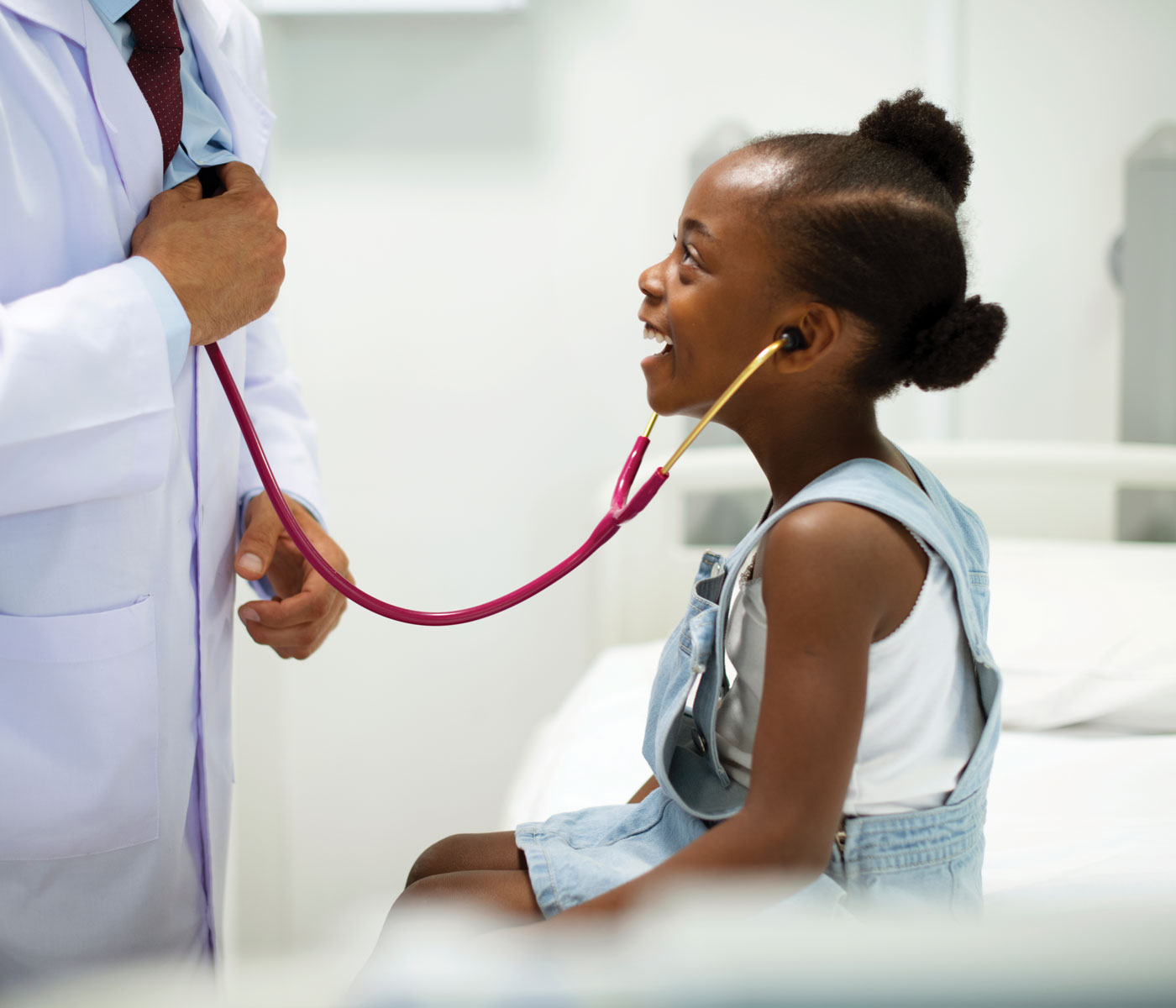 Little girl smiles as she listens to doctor's heart with stethoscope