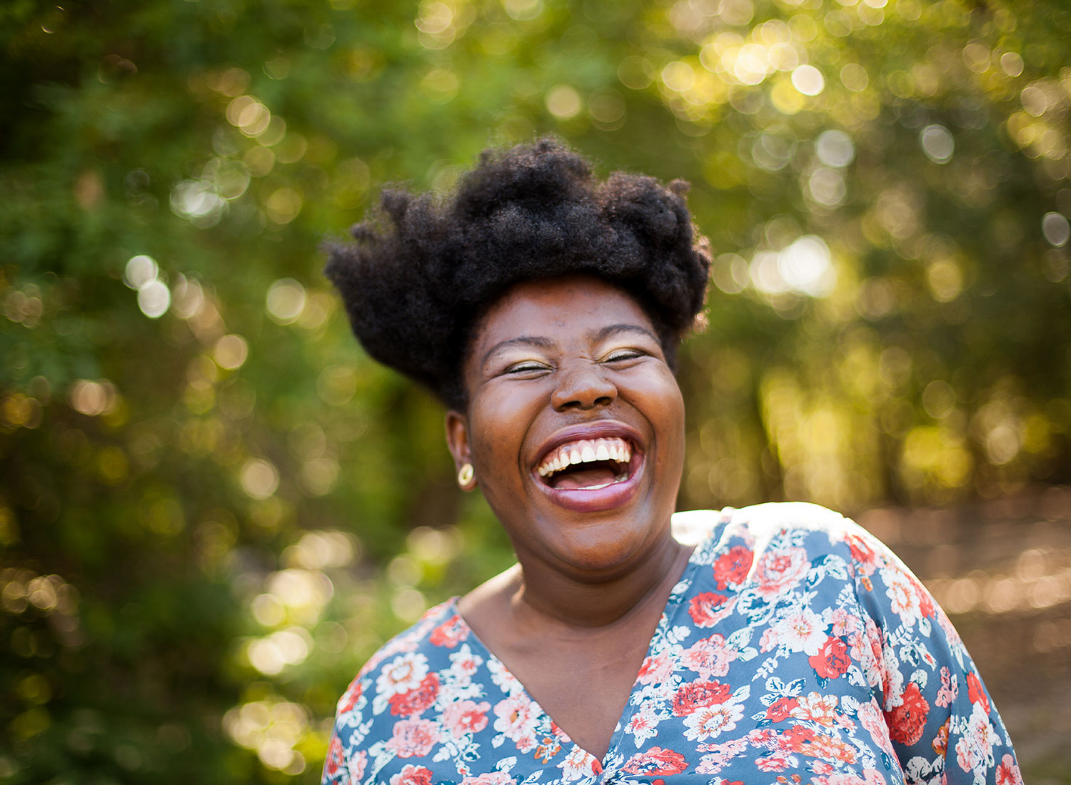 Black woman laughing under trees