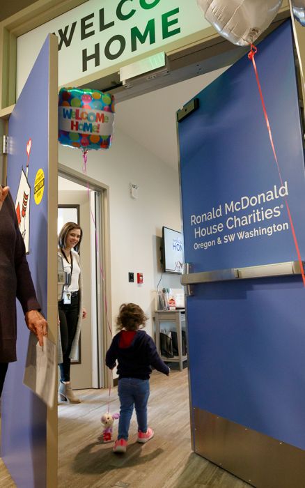 A little girl enters a room under a sign that says "welcome home."