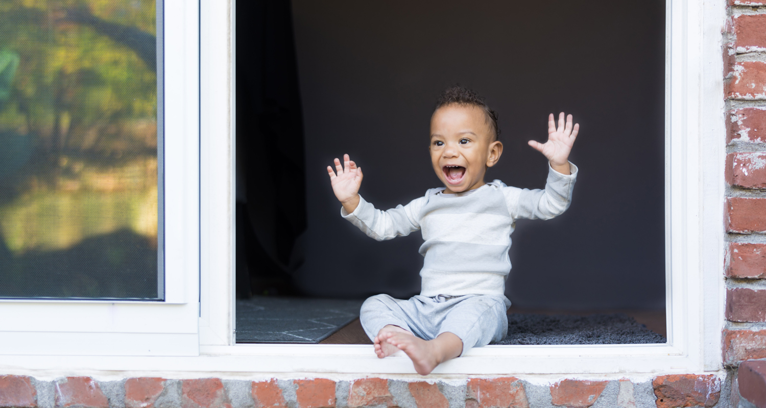 toddler boy grinning in a doorway