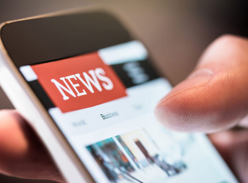 close-up of thumb scrolling through news on smartphone