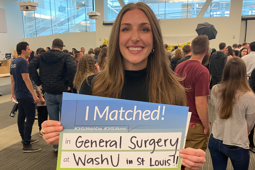 Woman holds a sign that says "I matched! General Surgery at Wash U in St. Louis!"