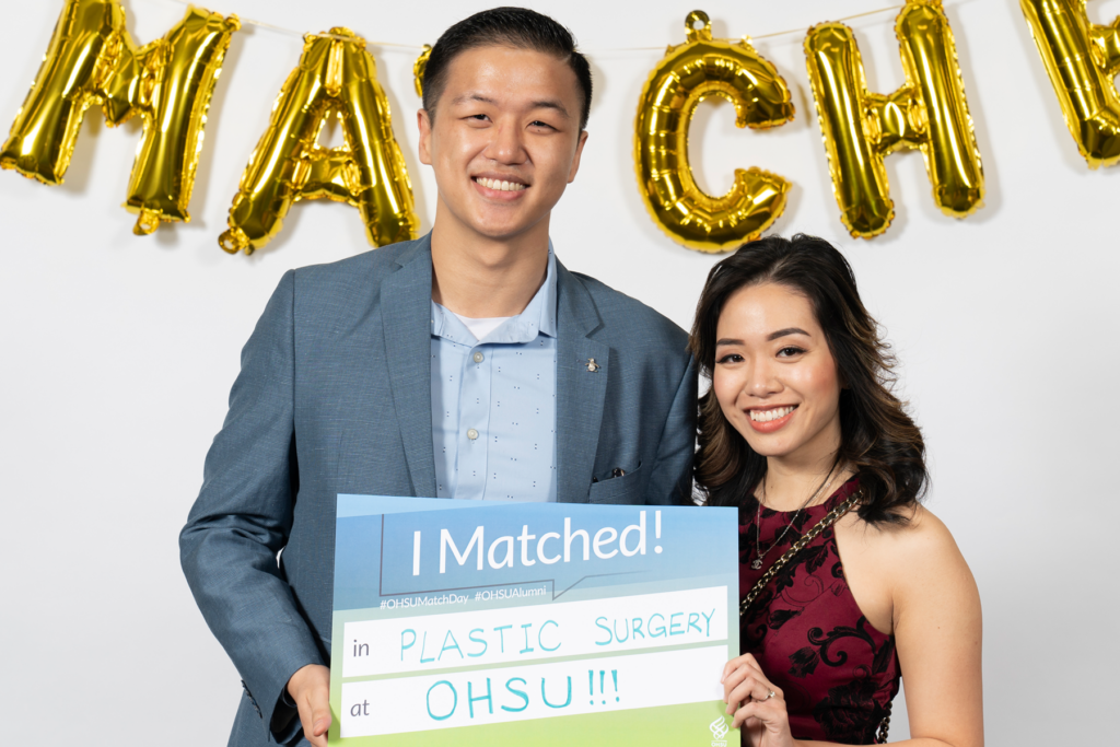 Couple holds sign that reads "I matched in plastic surgery" 