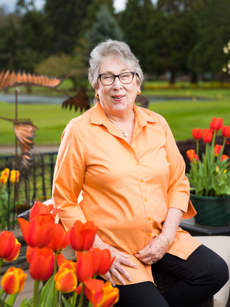 Older woman sits in her garden surrounded by red tulips