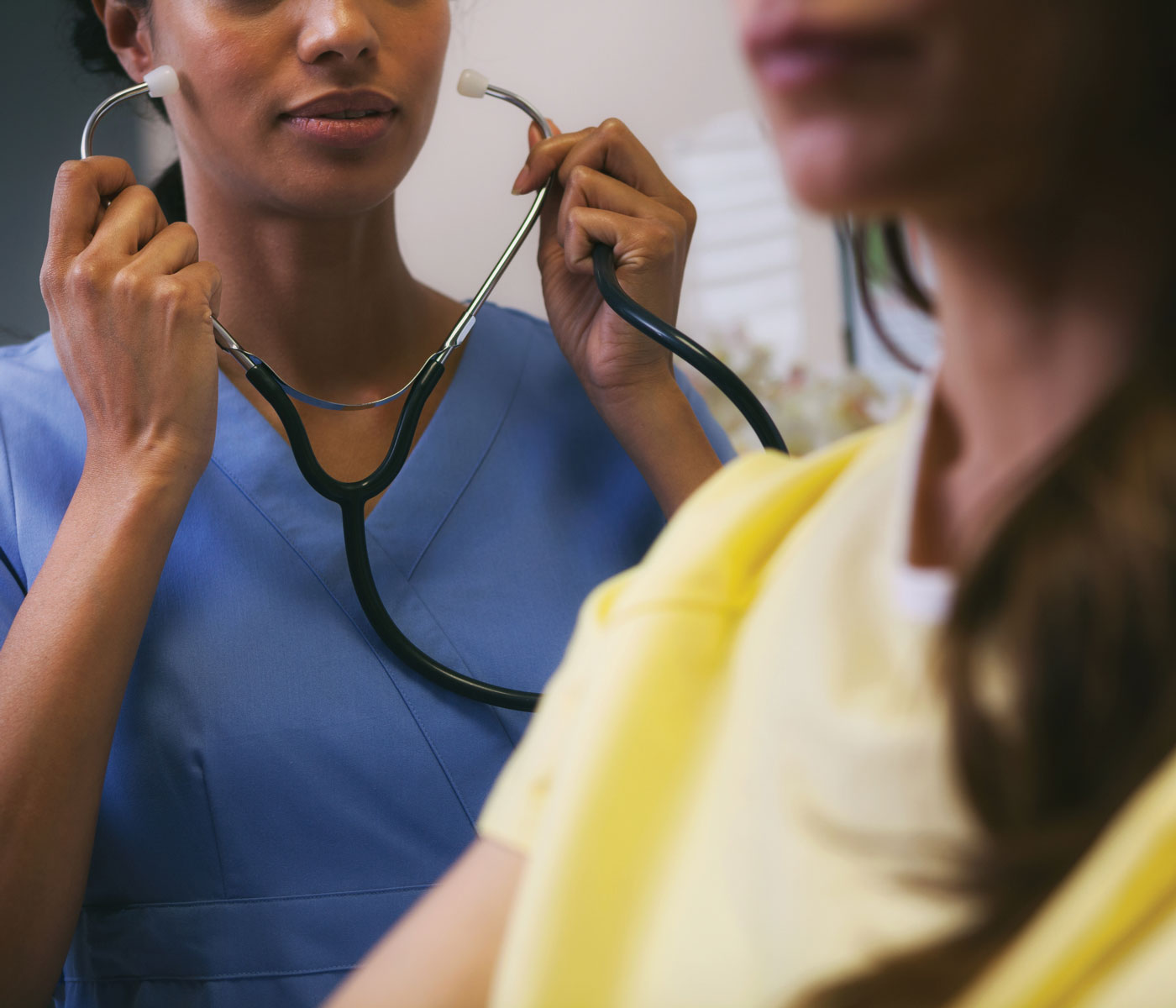 woman puts on stethoscope with another woman in the foreground
