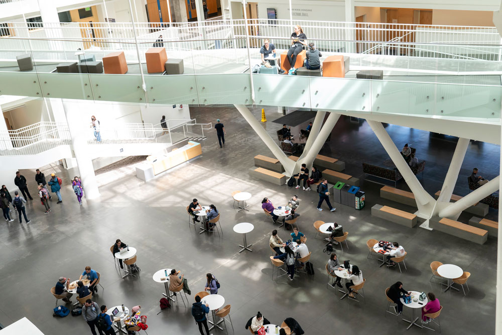 Overhead image of students eating and talking in the atrium of a building