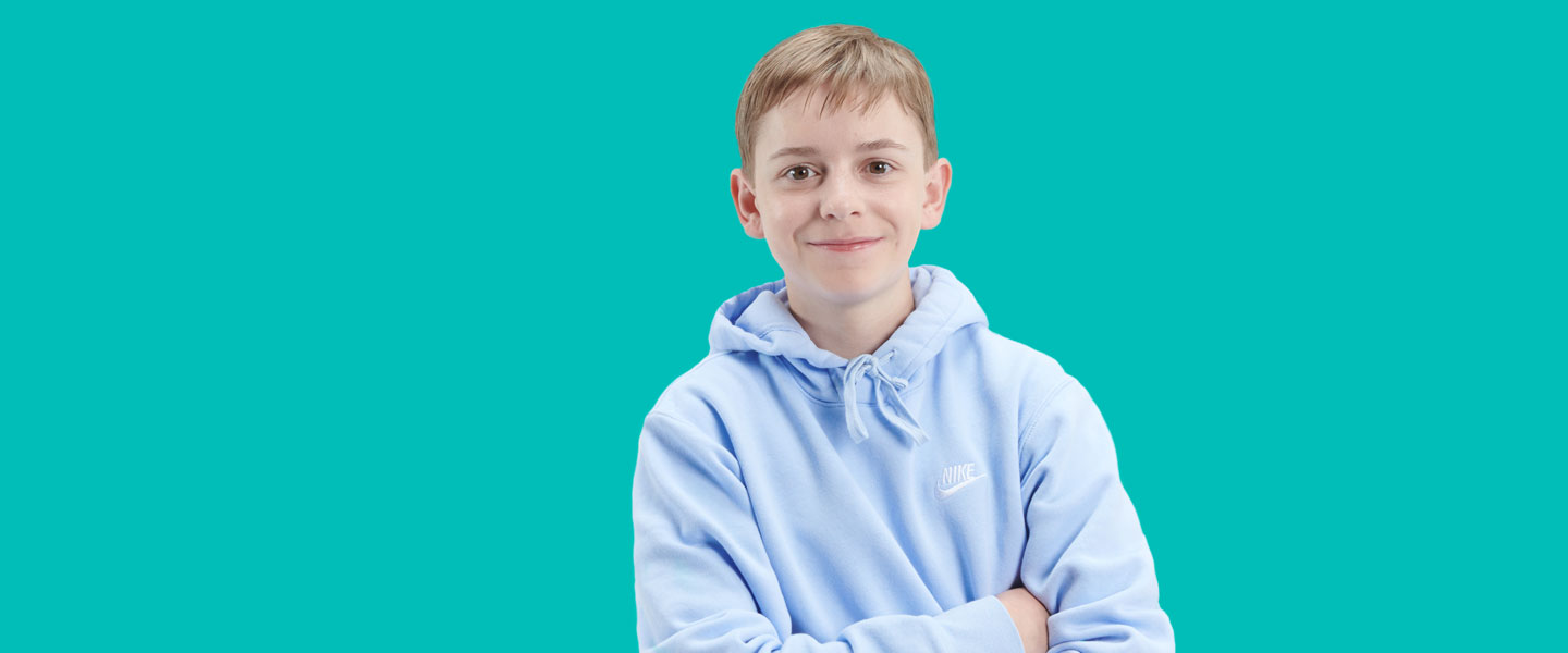 Emerson stands with his arms crossed in front of a turquoise background