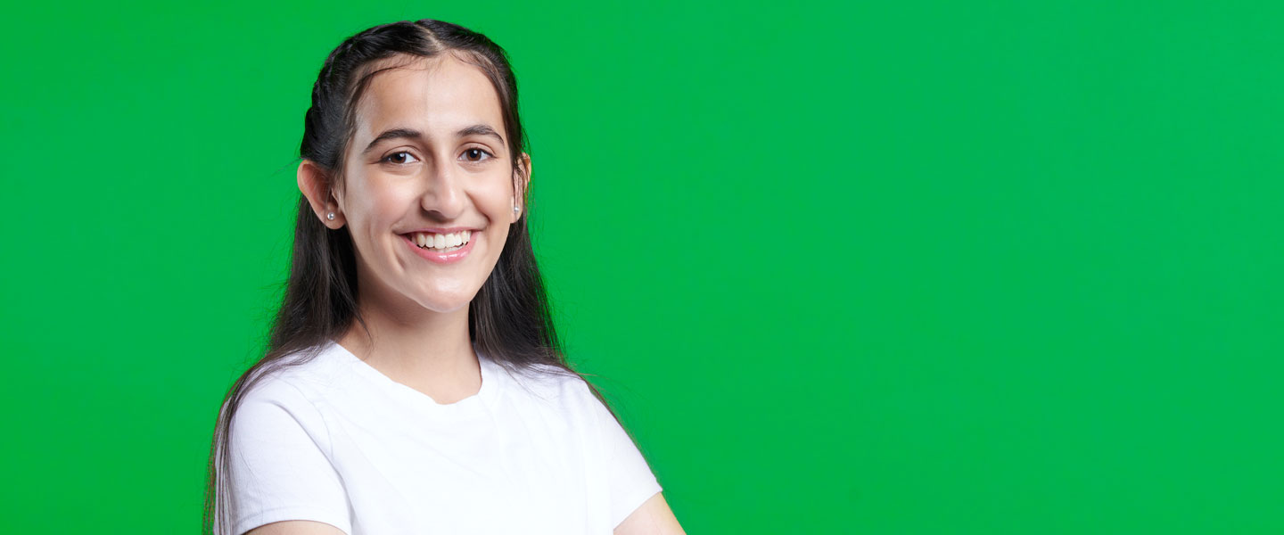 Riddhi smiles in front of a bright green background