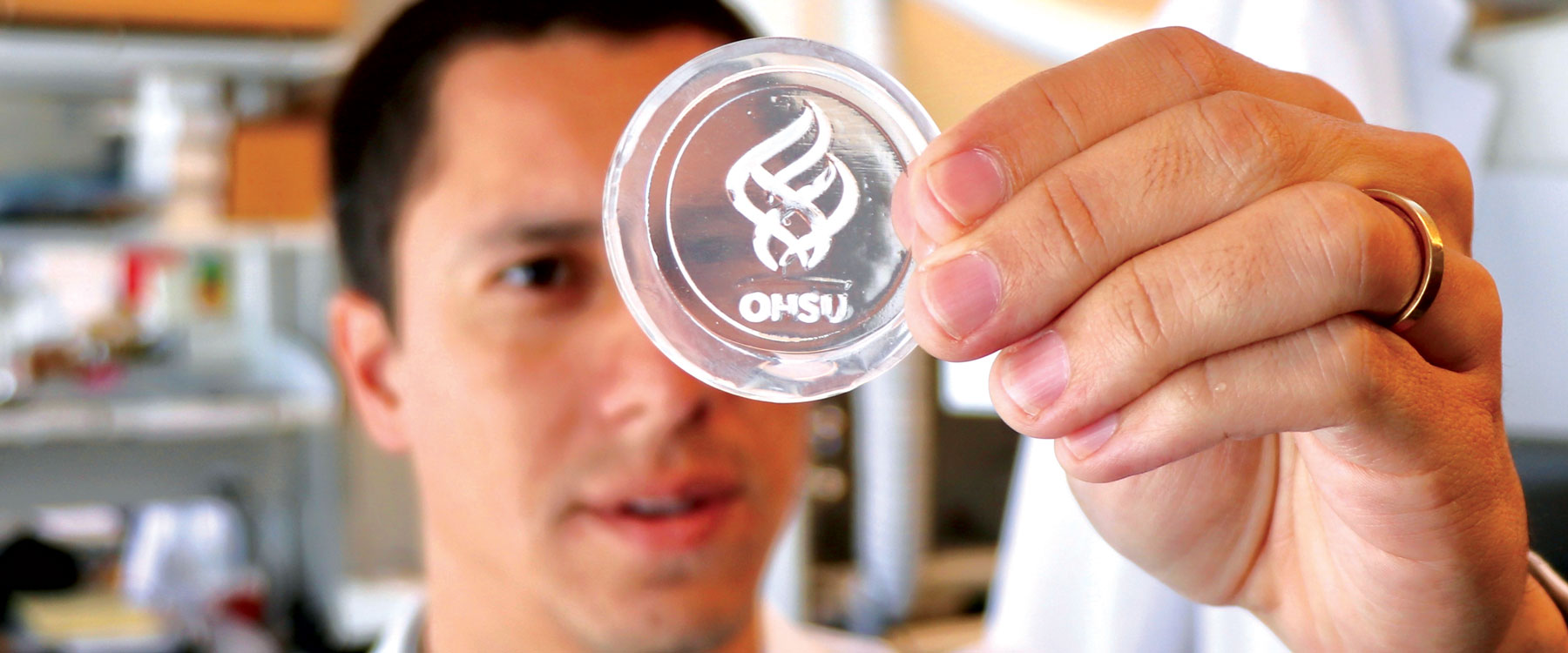 Researcher holds up a dish showing the OHSU logo grown from engineered bone tissue