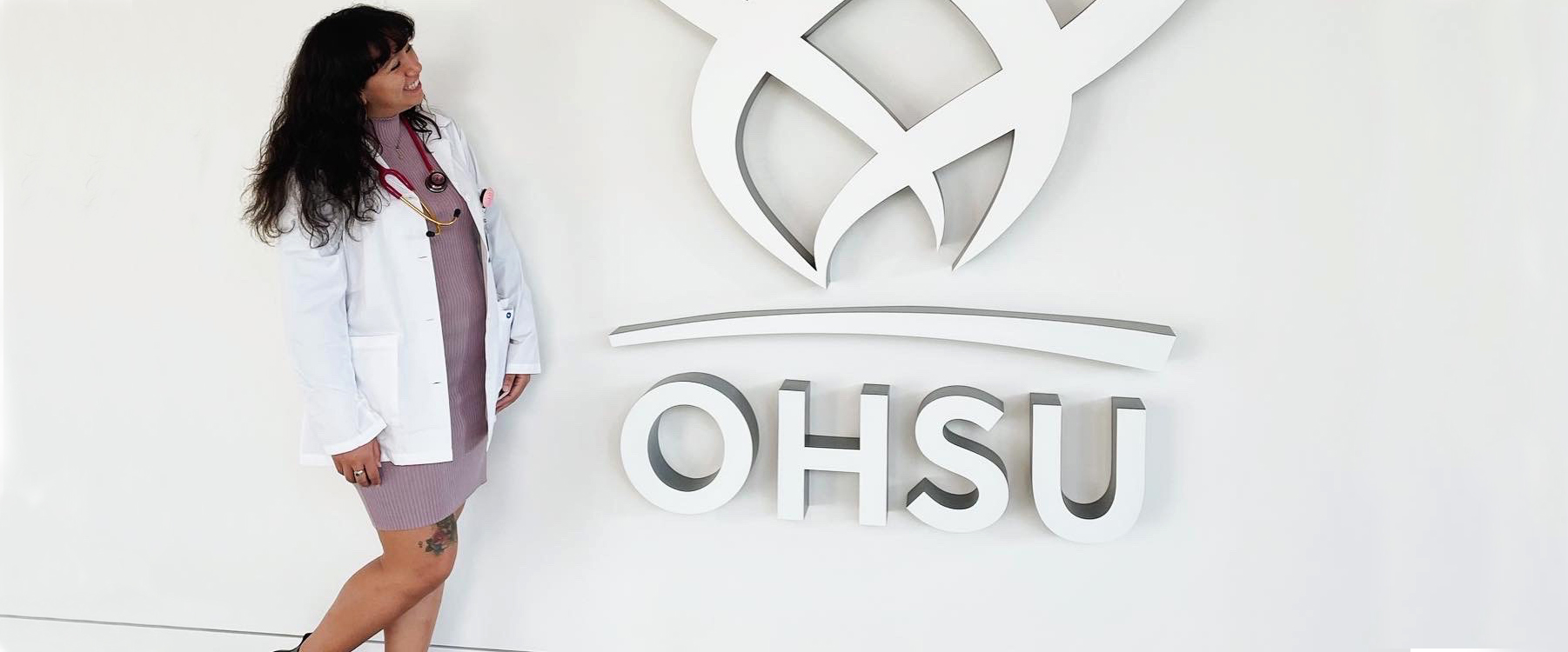 Lillya Roldan standing in front of the OHSU logo