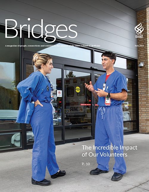A man and a women wearing scrubs standing in front of a hospital entrance having a conversation.