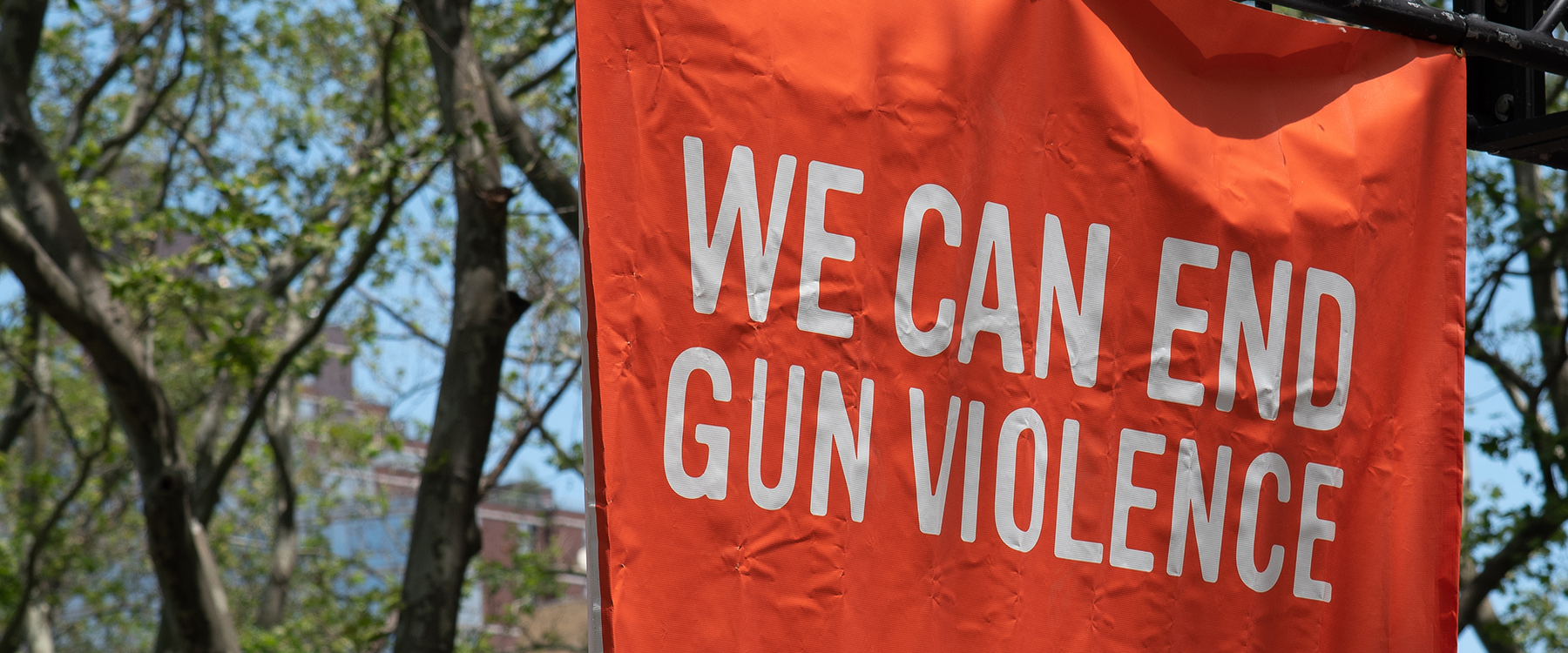 Orange sign that reads "we can end gun violence"