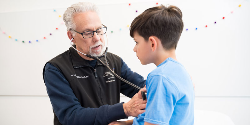 Pediatric cardiologist Michael Silberbach, M.D., checks a child's heartbeat.