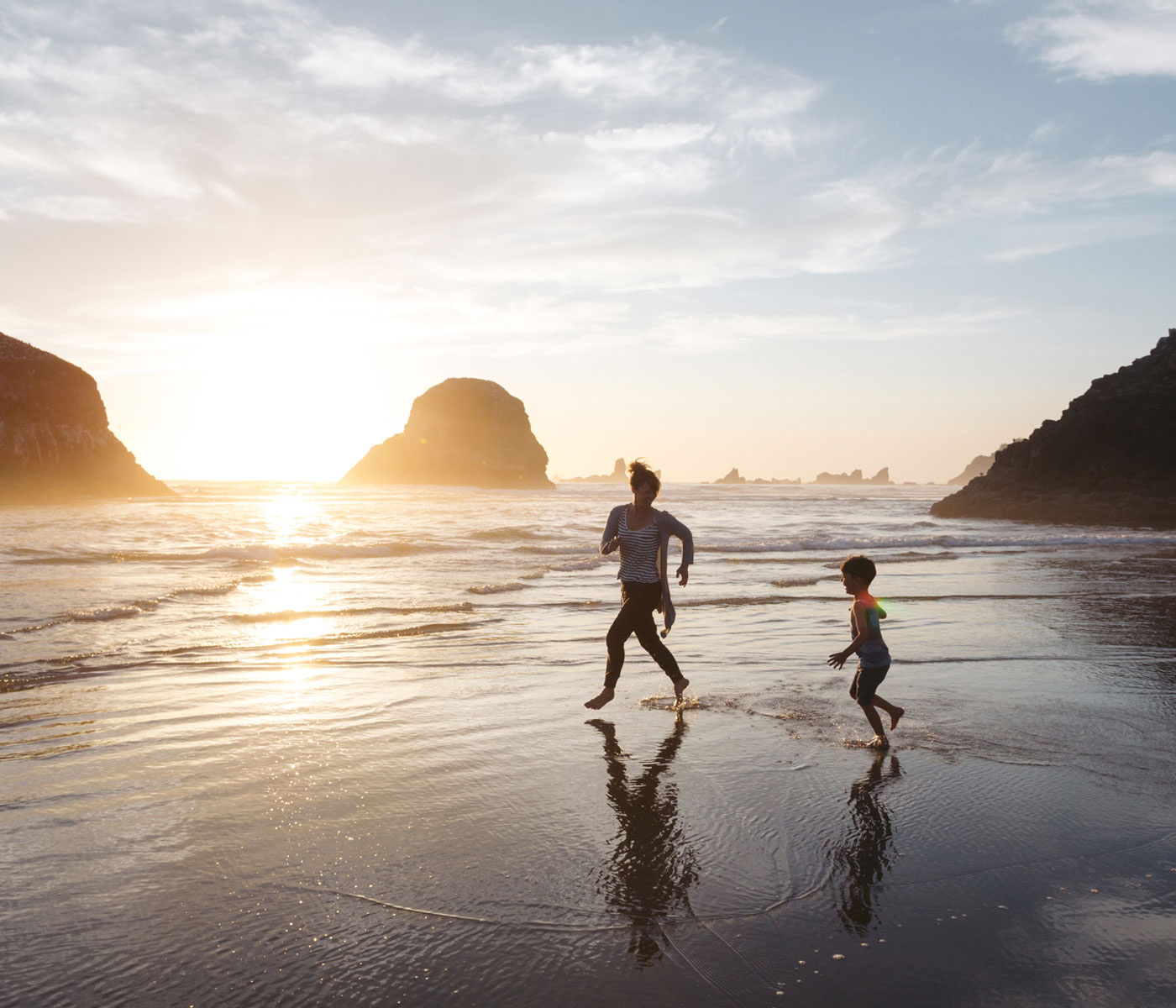 A young mom plays on the beach with her child in the setting sun