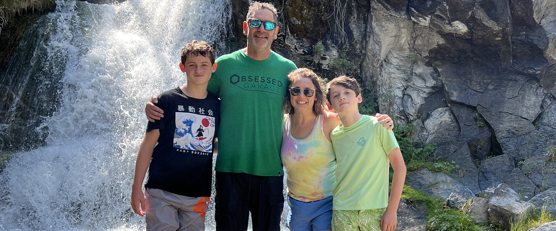 Amy Corcoran stands in front of a waterfall with her family