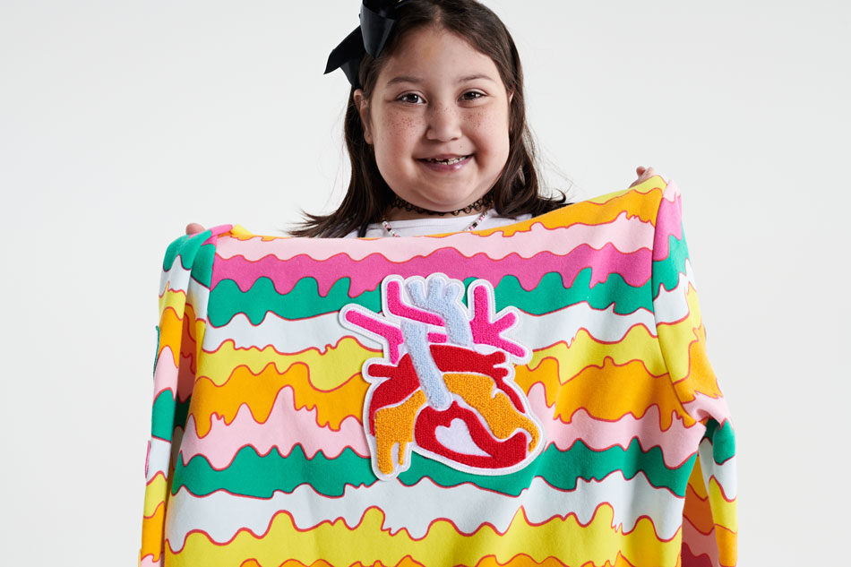 Hailey shows off her colorful sweatshirt design, which features squiggly stripes in green, pink, orange and yellow with a patch of a human heart
