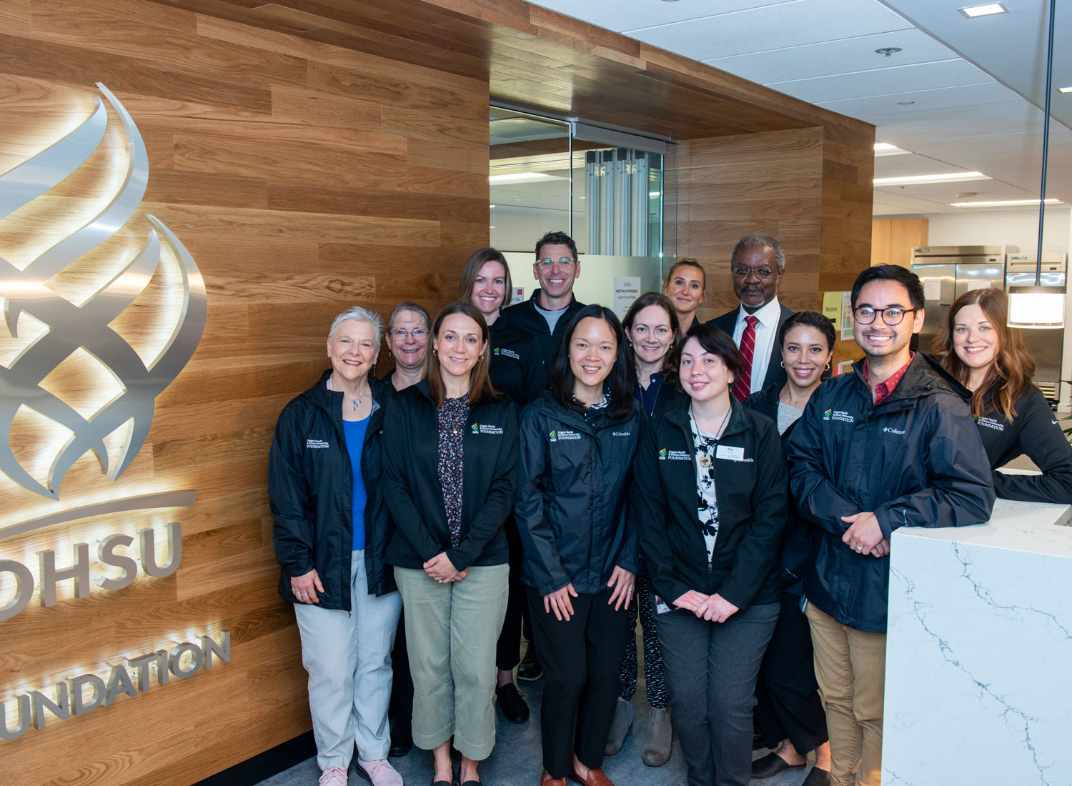 Members of the OHSU Foundation staff pose for a photo in the foundation lobby with OHSU President Danny Jacobs, M.D.