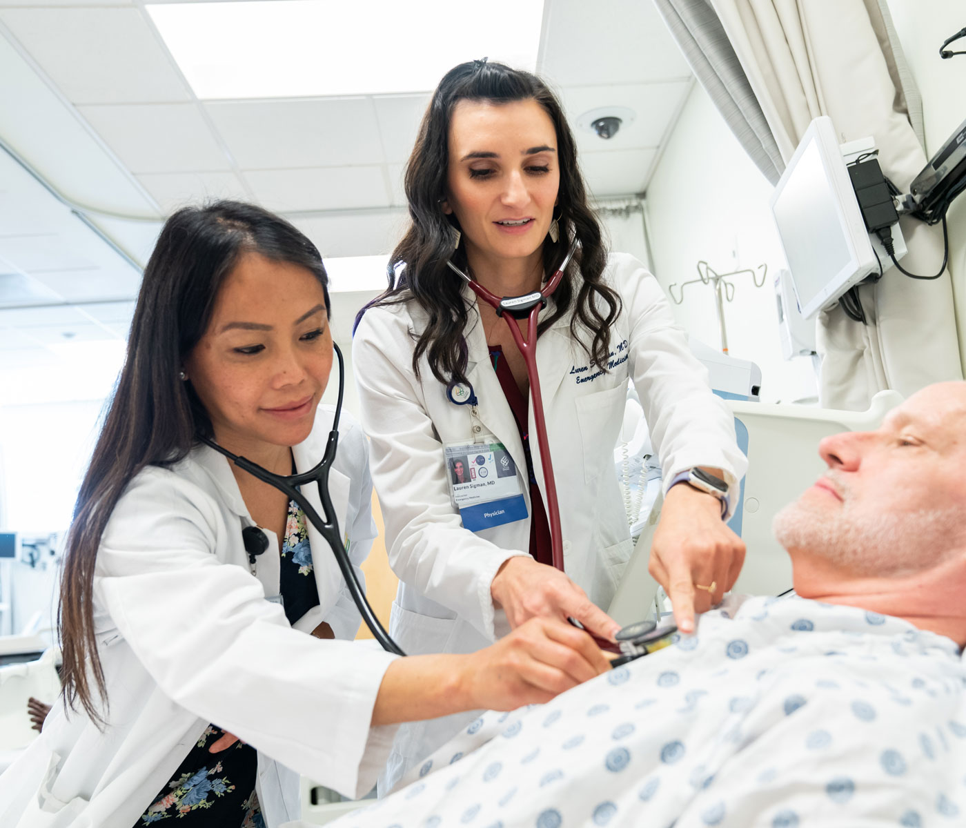 A faculty member shows a medical student how to examine a patient in a simulation lab