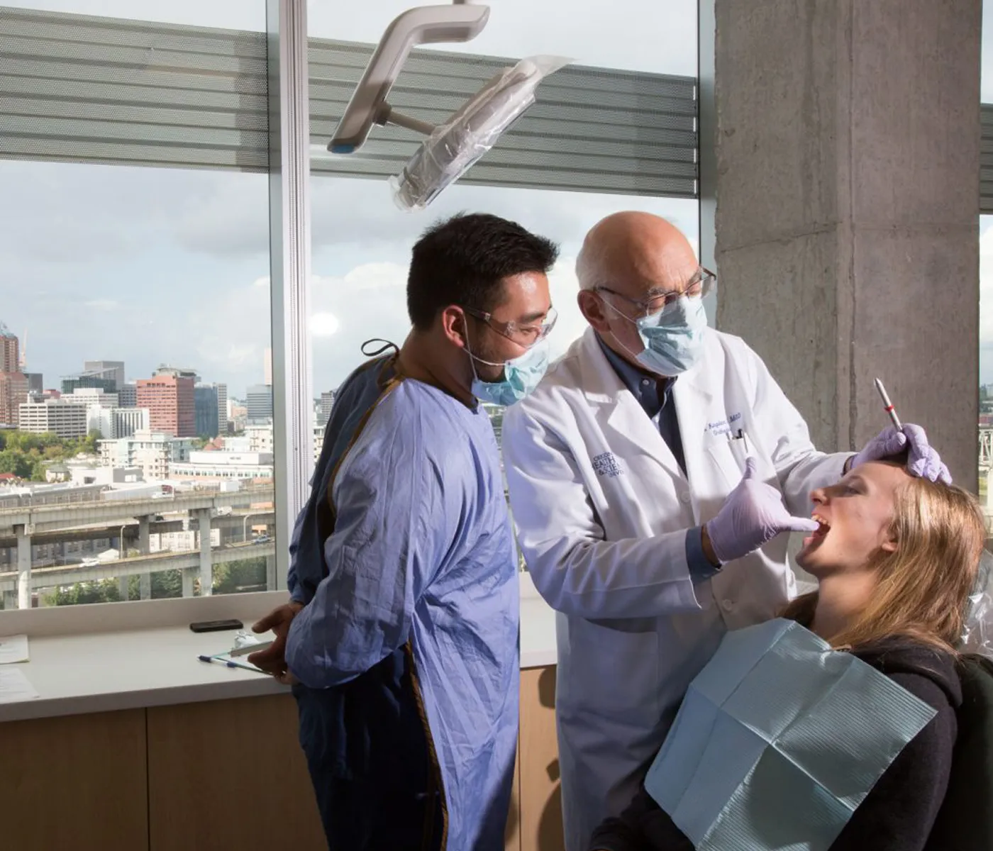 School of dentistry student observes faculty member conducting a procedure on a patient