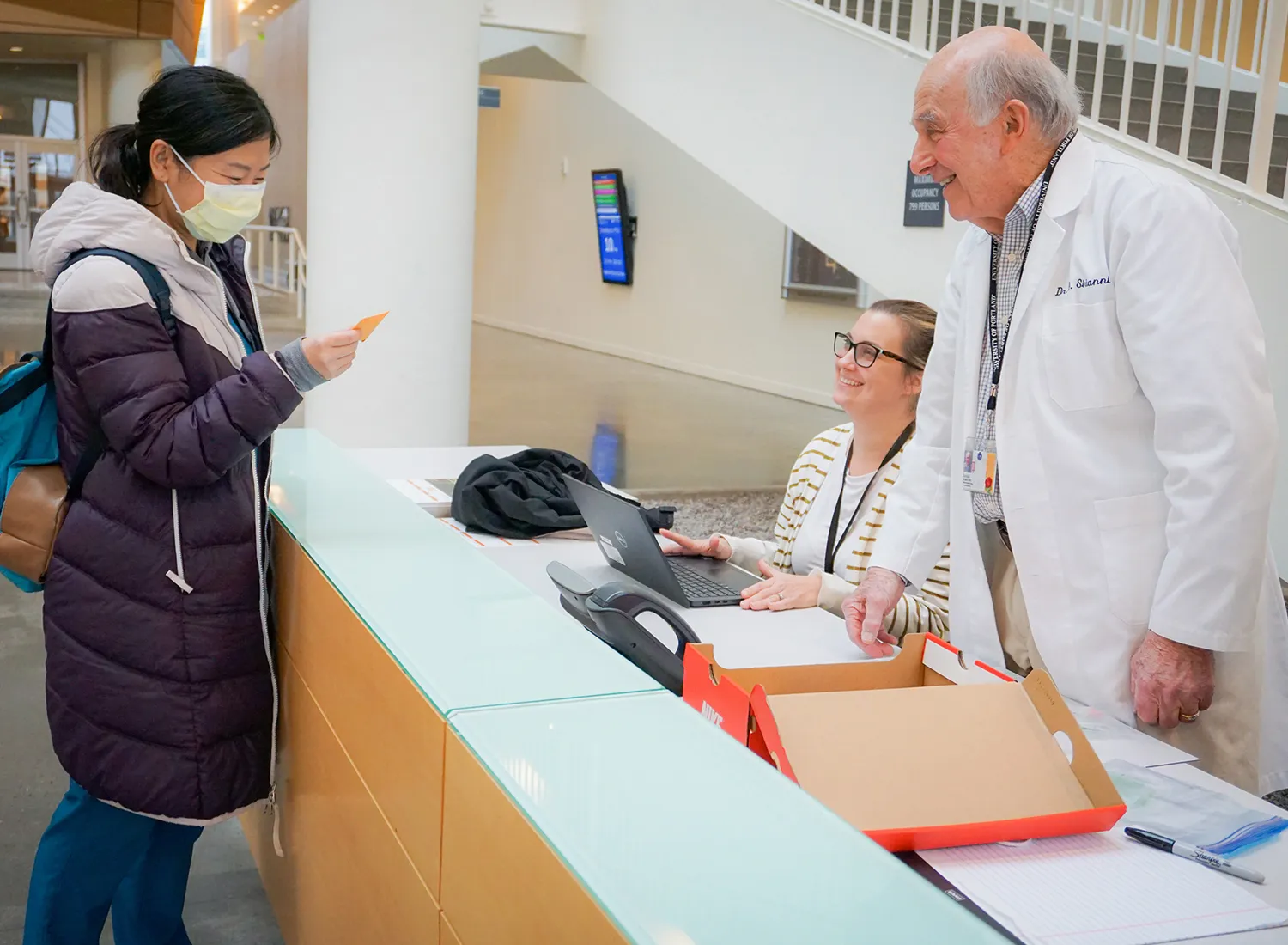 School of Dentistry student receives envelope from two faculty members at a desk.