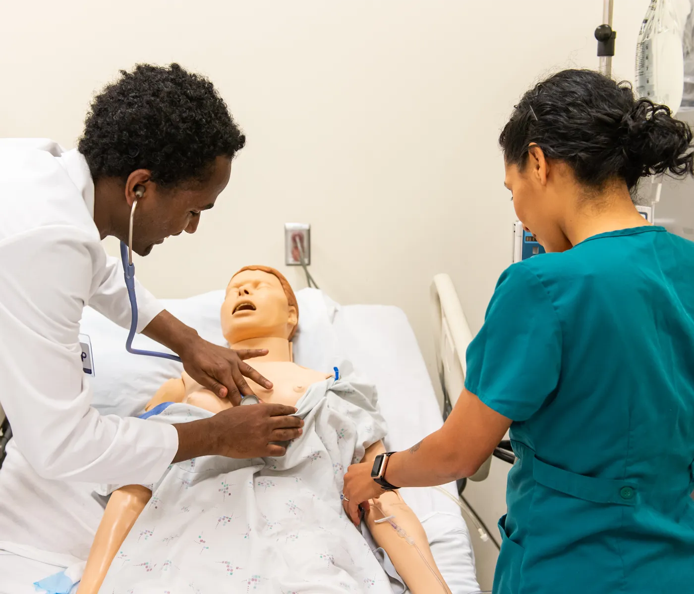 School of nursing students use stethoscope to check manikin.