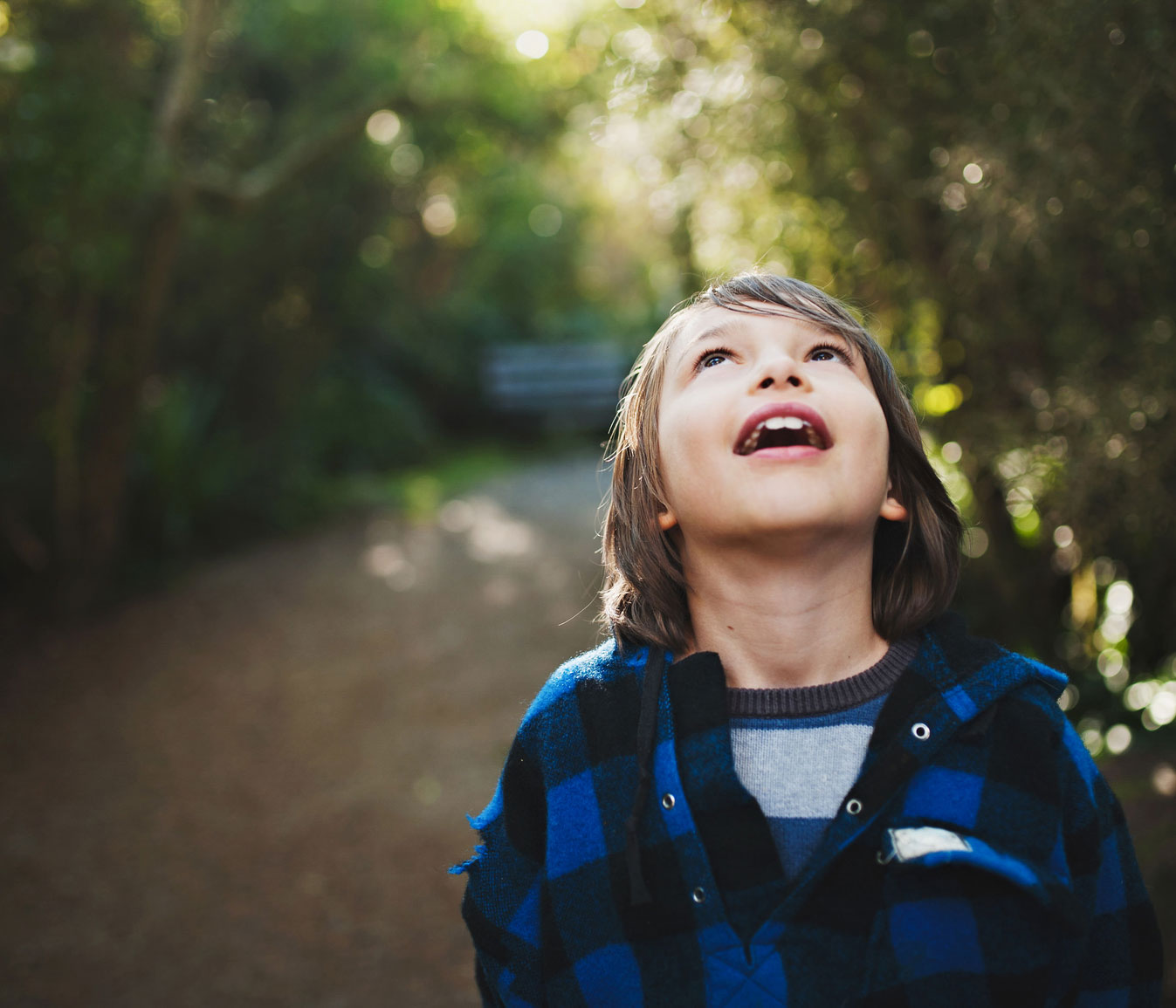 Young boy outdoors looks up at the sky