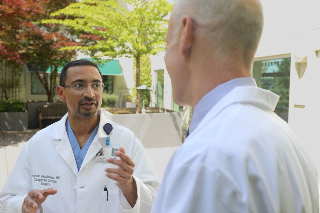 Ashok Muralidaran, M.D., an Associate Professor of Surgery and Pediatrics in the Division of Cardiothoracic Surgery in the OHSU School of Medicine, talks about comprehensive health care for kids with Lars Grosse-Wortmann, M.D., in a courtyard at Doernbecher Children's Hospital.