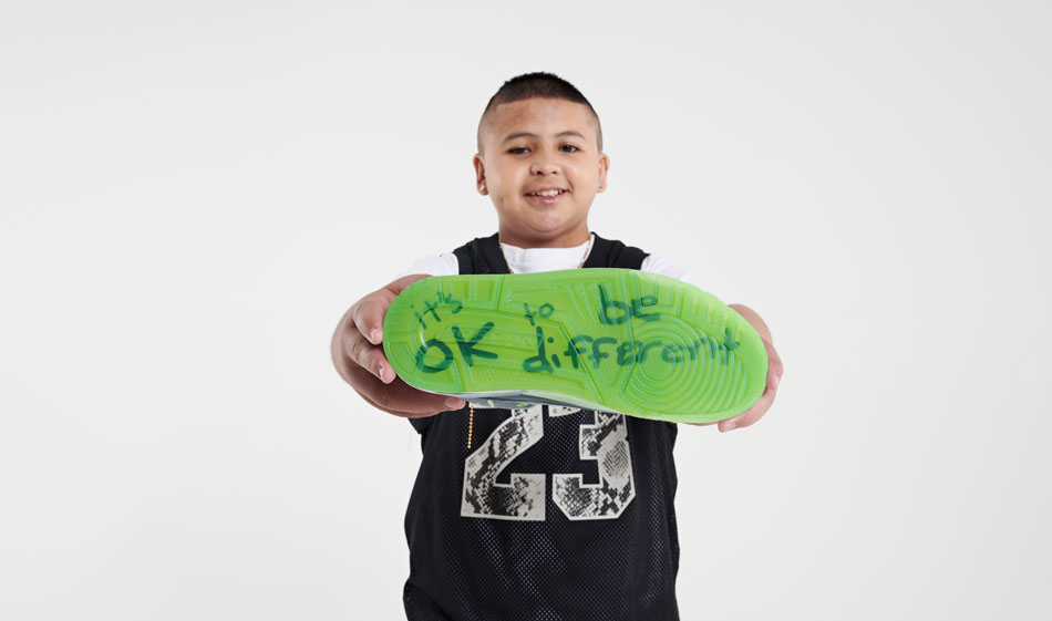 Hugo Covarrubias Molina holds up a shoe that says "it's ok to be different."