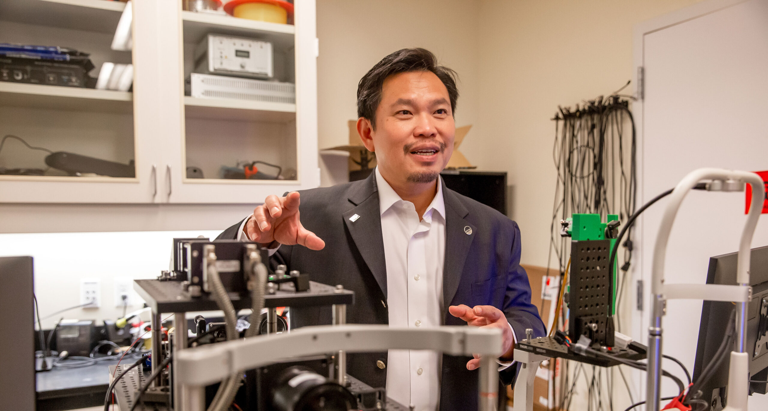 David Huang stands next to equipment in his lab.