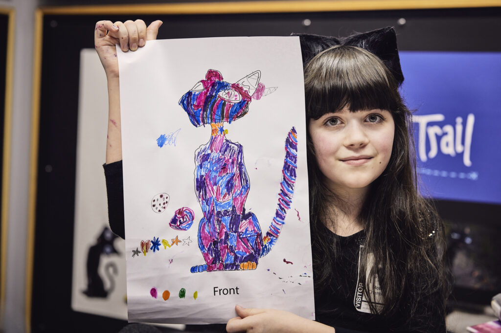 Rosie, wearing cat ears, displays her colorful cat design