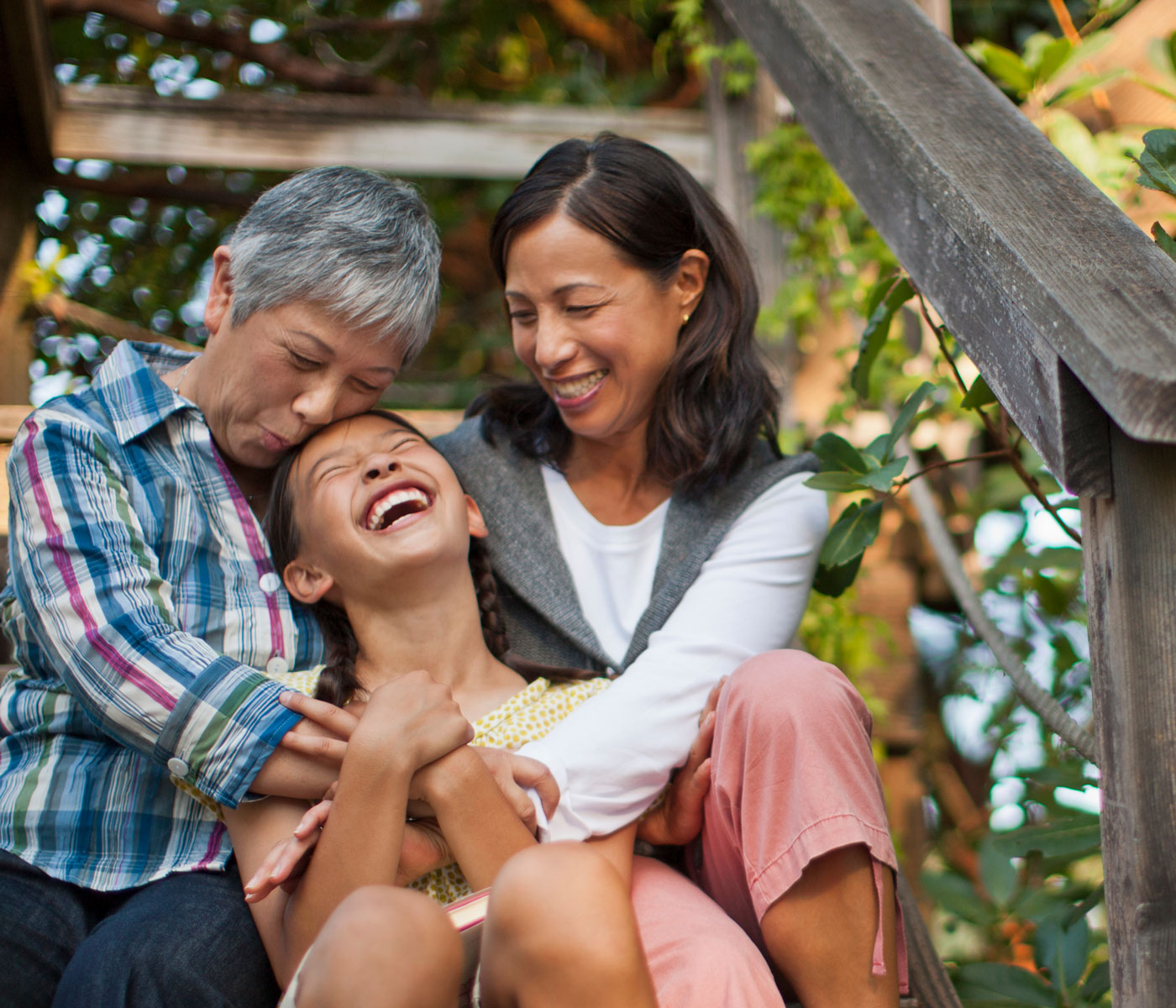 A young girl has a big grin as she's hugged by her mom and grandmother.