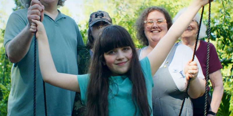 Rosie outside on a swing with her family