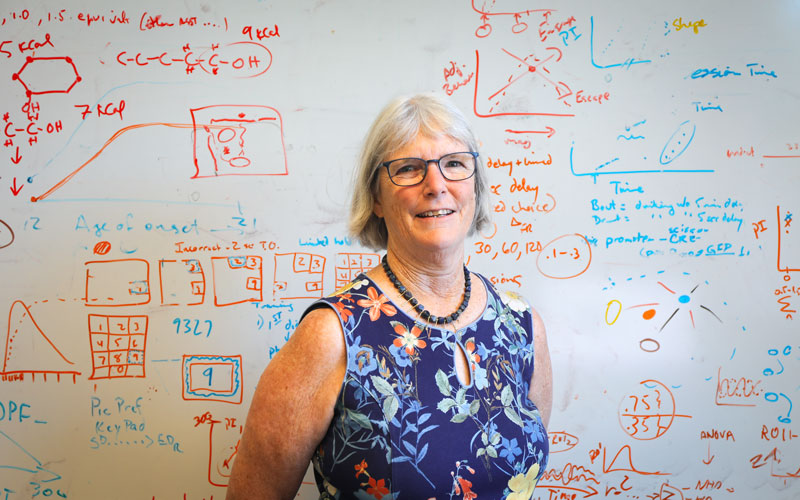 Kathy Grant stands in front of a white board coered with calculations