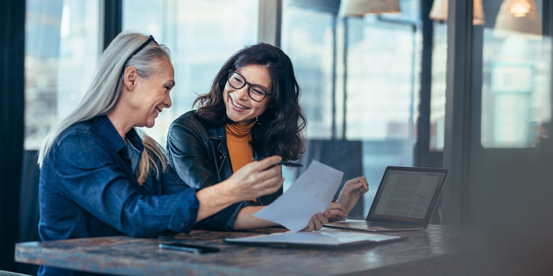 Two women discuss something pleasant in an office setting