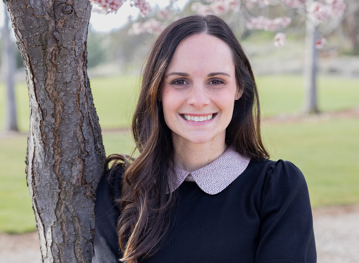 Kristi Runberg standing in a park with cherry blossoms in the background.