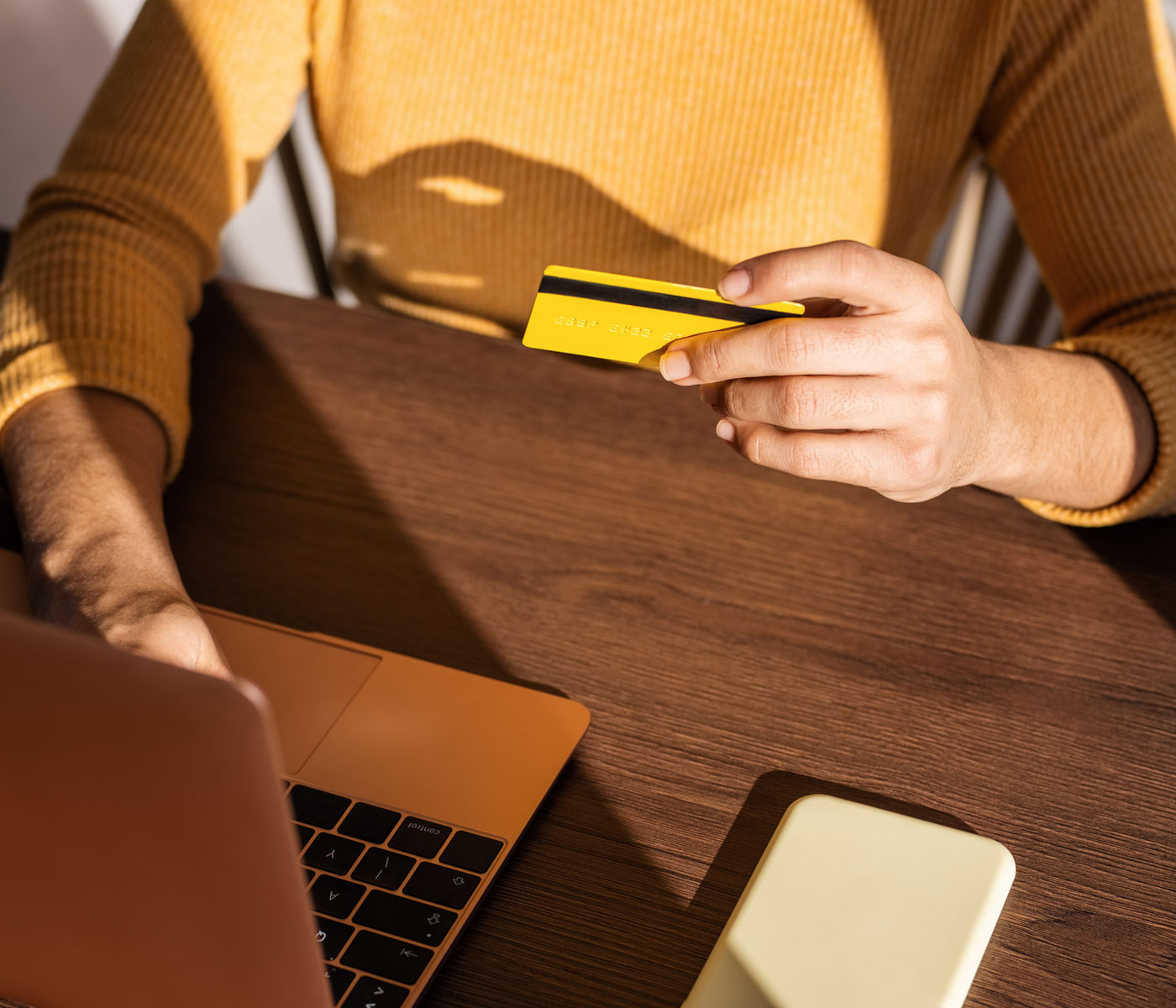 woman holding a credit card and typing on laptop