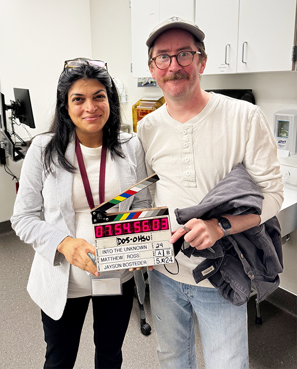 Matthew Ross with Divya Sood holding a film slate.