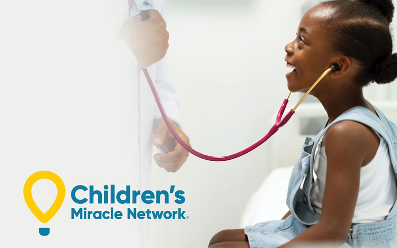 Young girl wears stethoscope to hear doctor's heart - Children's Miracle Network logo