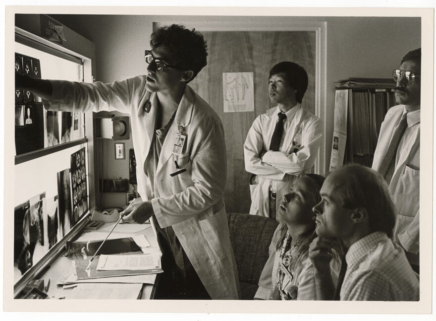 A group of four men and women look at x-rays displayed on a wall.