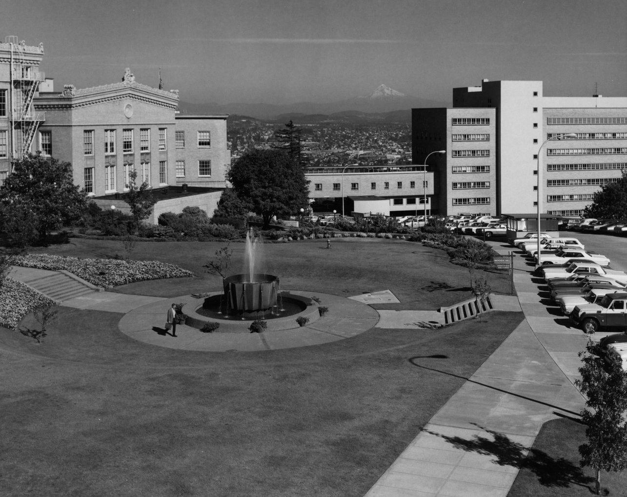 A black and white aerial view of the Alumni Fountain and the Mackenzie Hall lawn with Mt. Hood in the distance.